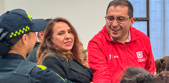 Segundo encuentro de coordinadores de zonas seguras en la localidad de Puente Aranda “Un policía, una mujer y el Alcalde de Puente Aranda Víctor Cruz se saludan durante el Segundo Encuentro de Coordinadores de Zonas Seguras, en un espacio comunitario de diálogo y participación ciudadana.”