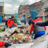 “Alcaldía de Puente Aranda participa en una jornada de limpieza en la calle, retirando basuras y escombros acumulados junto a un muro pintado, en la zona a espaldas de la Cárcel Modelo en Puente Aranda.”